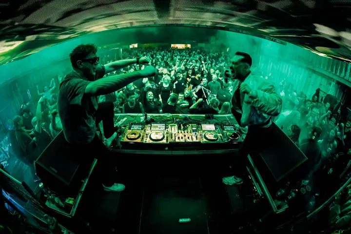 Zwei Acts am DJ-Pult im grünen Licht